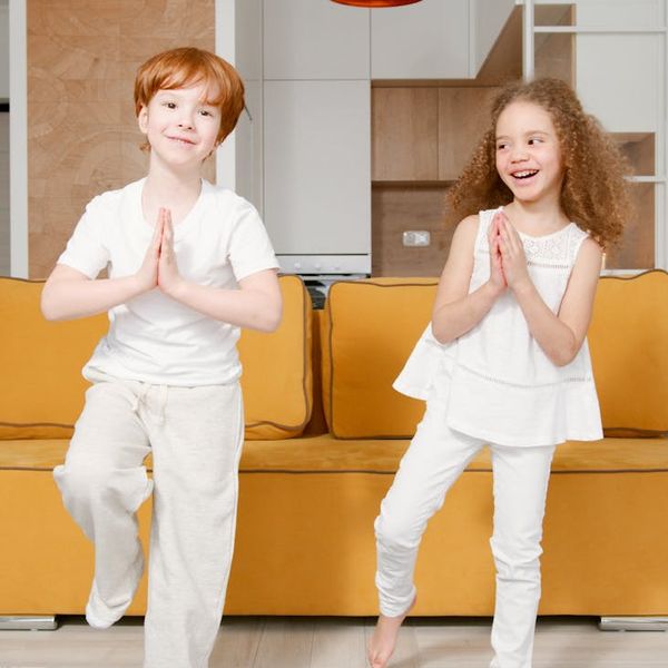 Child standing calmly in a tree yoga pose, showing balance.